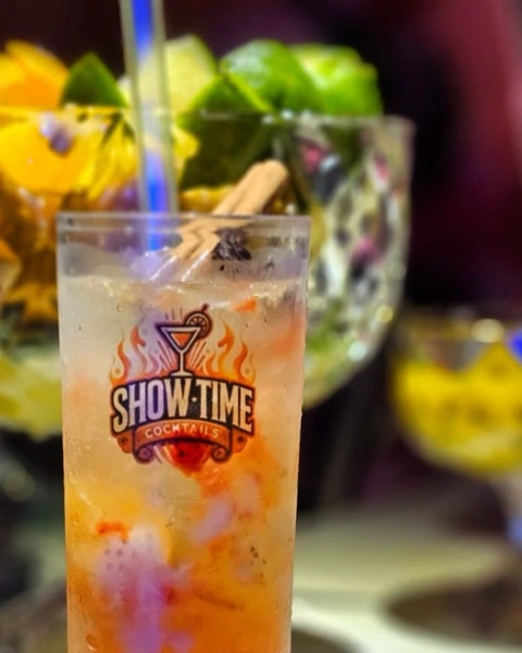 Drink cítrico servido em copo alto com a marca Showtime Cocktails