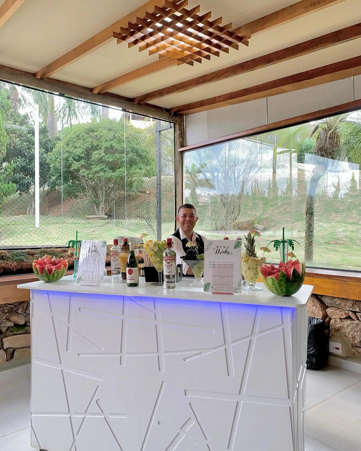 Balcão de bar montado em salão de festas com vista para o jardim