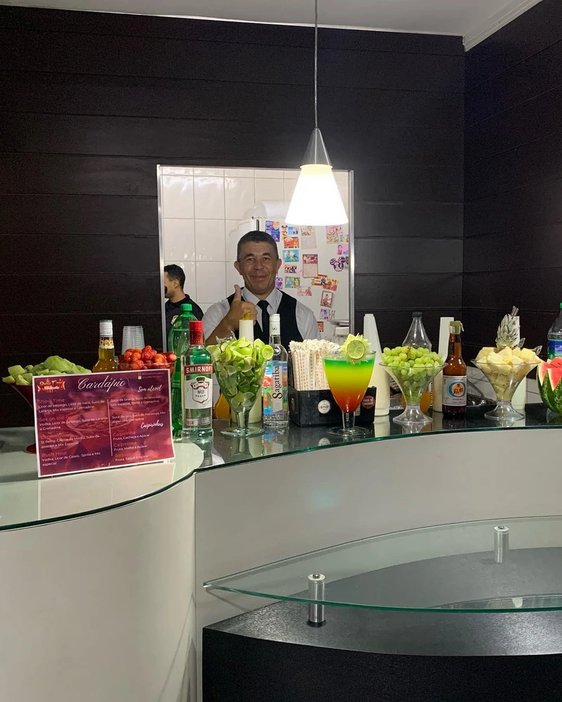 Bar curvo montado com bartender atendendo ao fundo